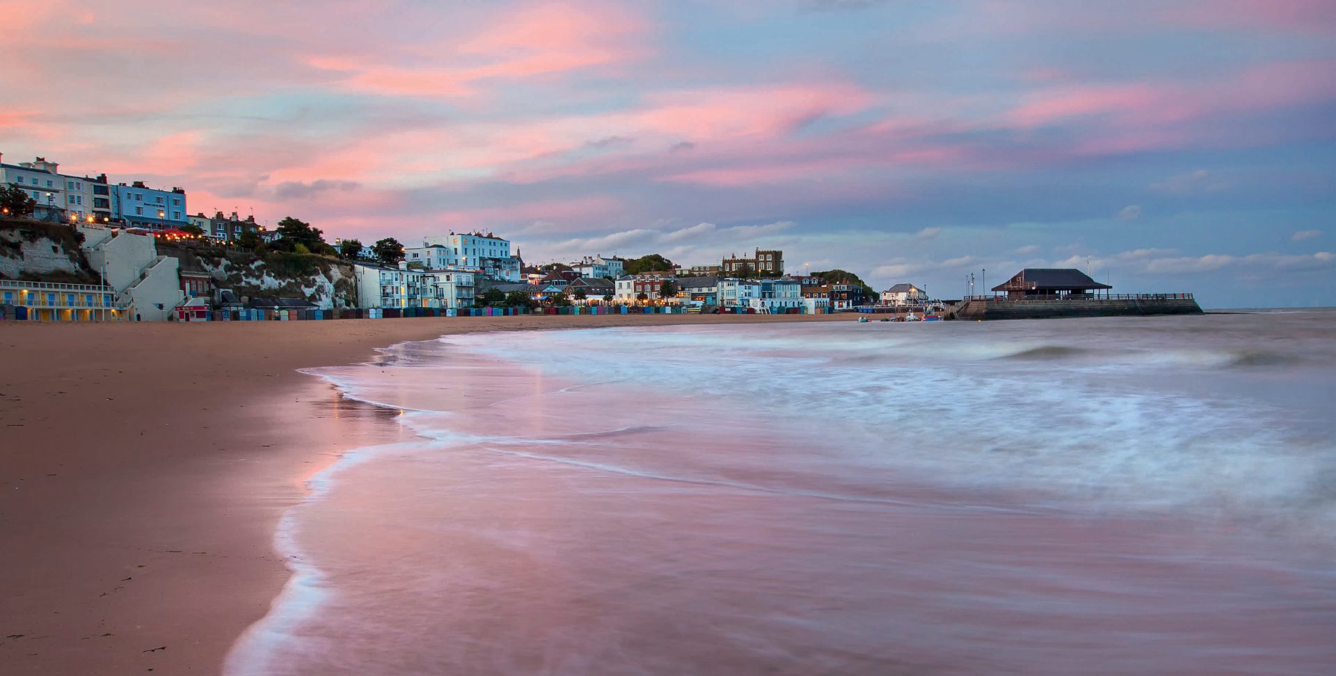 Viking Bay in Broadstairs, Kent at sunset with town lit up in the